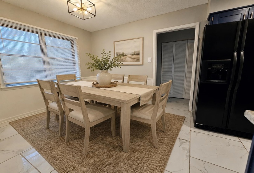 Dining area featuring a modern geometric ceiling light fixture, white tile flooring, and a black side-by-side refrigerator