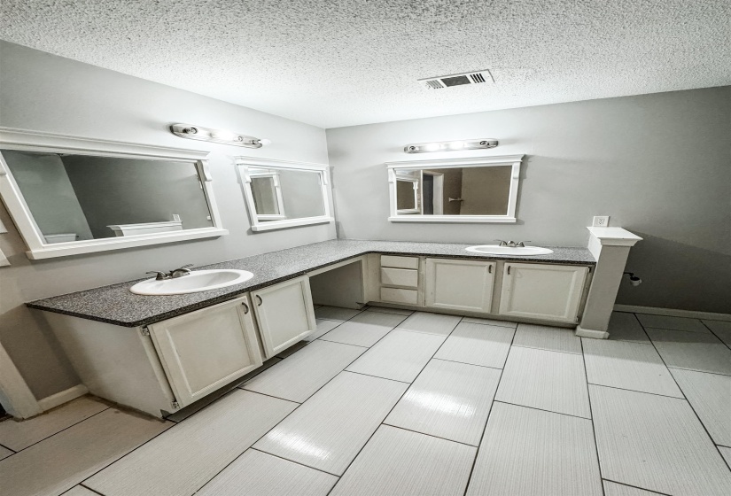 Bathroom with a textured ceiling, tile patterned floors, and vanity
