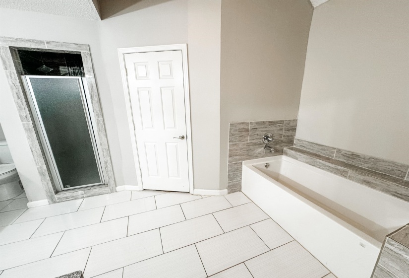 Bathroom with a textured ceiling, plus walk in shower, toilet, and tile patterned flooring