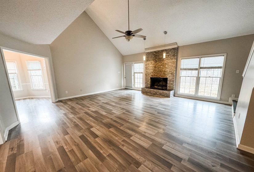 Unfurnished living room with high vaulted ceiling, a fireplace, hardwood / wood-style floors, and ceiling fan