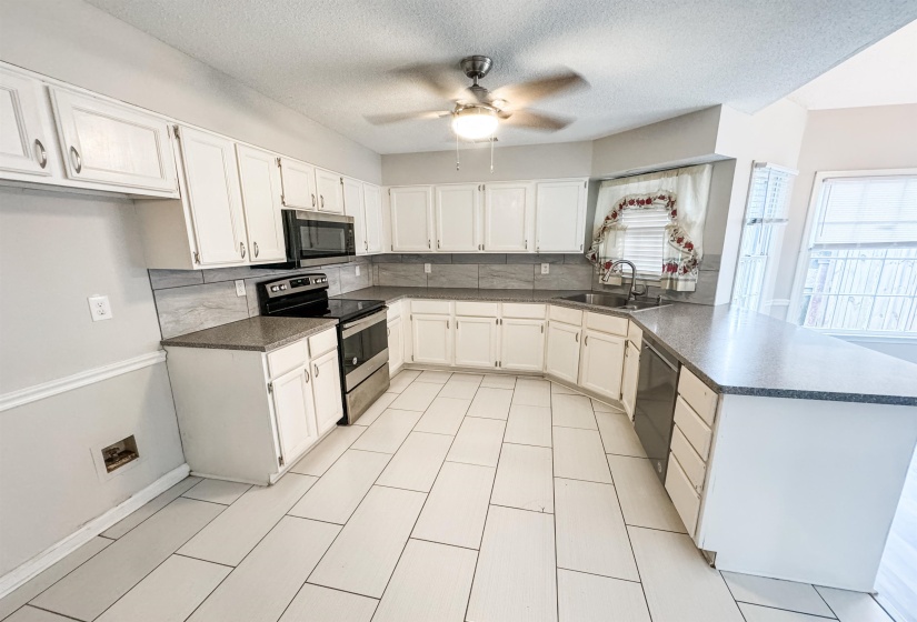 Kitchen featuring appliances with stainless steel finishes, white cabinets, ceiling fan, sink, and kitchen peninsula