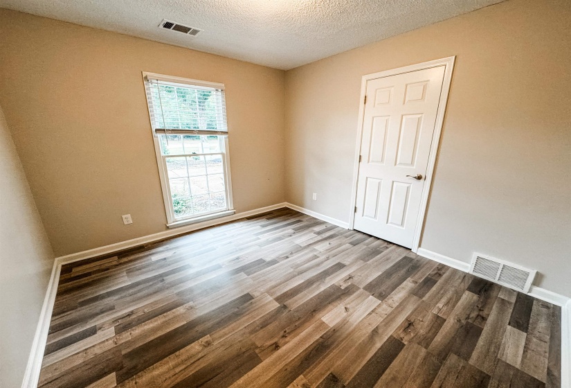 Unfurnished room featuring hardwood / wood-style flooring, a textured ceiling, and plenty of natural light
