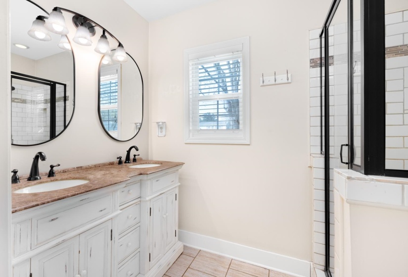 Bathroom with a shower stall, double vanity, healthy amount of natural light, and light tile patterned floors