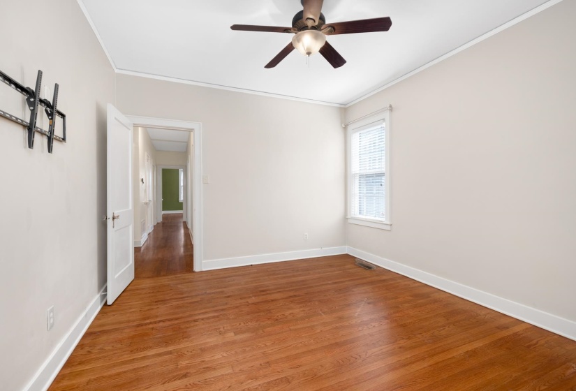 Empty room with wood finished floors, crown molding, and ceiling fan