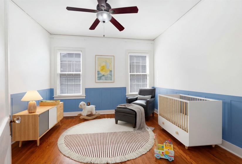 Living area with wood finished floors, a wainscoted wall, and a ceiling fan