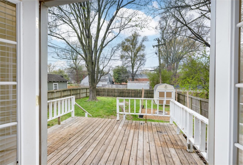 Wooden terrace with a storage unit and a fenced backyard