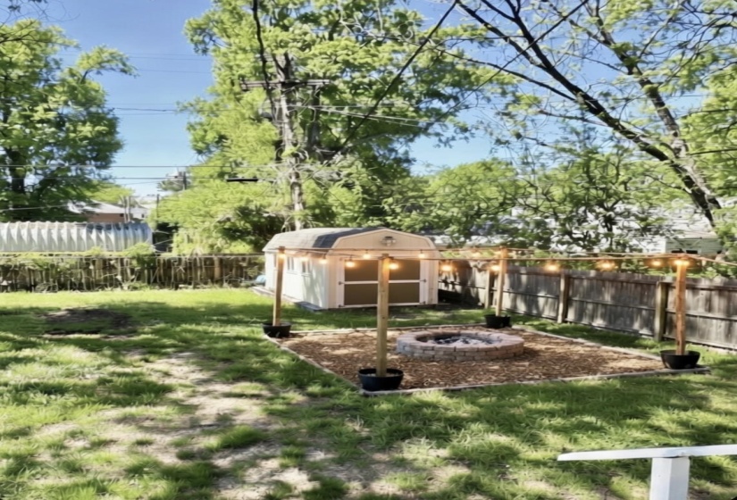Fenced backyard with an outdoor fire pit and a storage shed