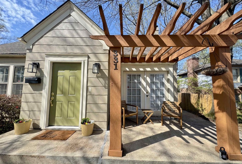 Doorway to property with roof with shingles and a pergola