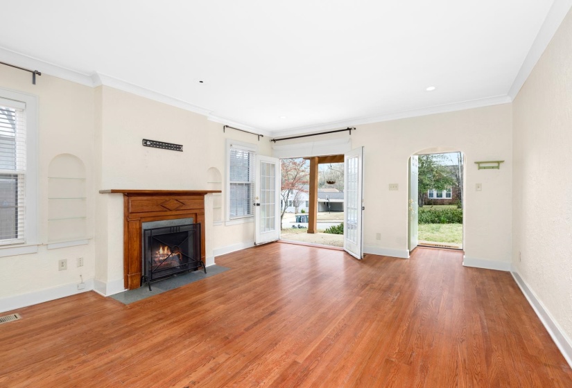 Unfurnished living room featuring a fireplace with flush hearth, wood finished floors, ornamental molding, arched walkways, and recessed lighting