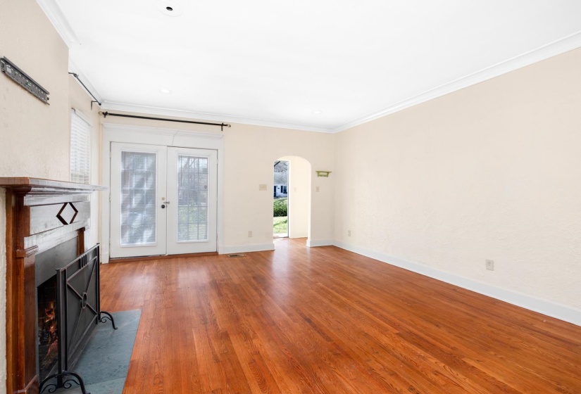 Unfurnished living room with arched walkways, hardwood / wood-style floors, ornamental molding, plenty of natural light, and french doors