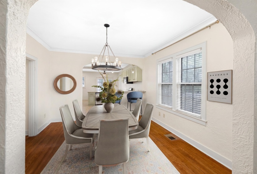 Dining area with arched walkways, a textured wall, ornamental molding, wood finished floors, and a chandelier