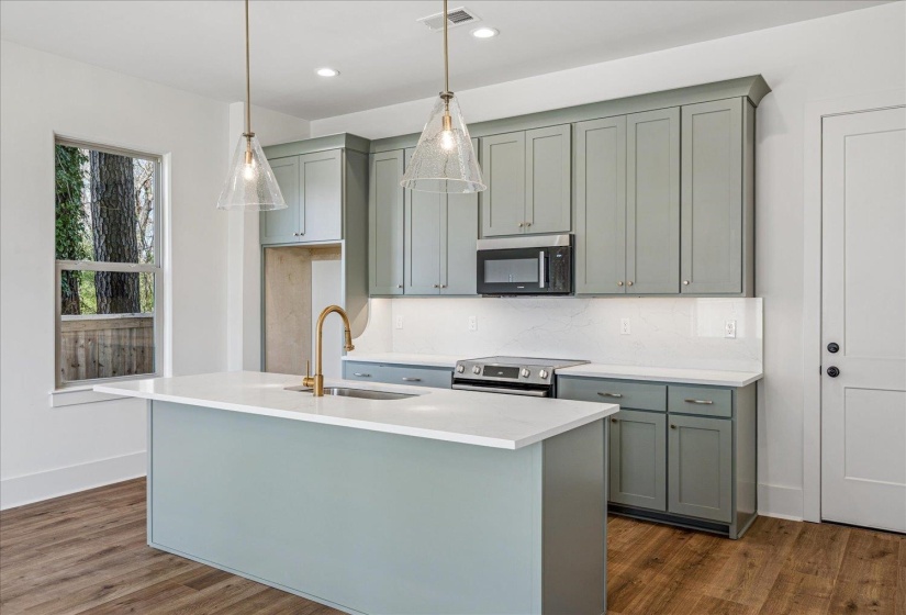 Kitchen with stainless steel appliances, dark wood-style flooring, an island with sink, and light stone counters