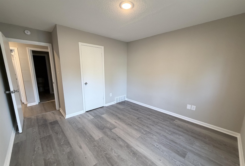Interior room featuring contemporary wood-finish flooring, neutral-toned walls, and white baseboards