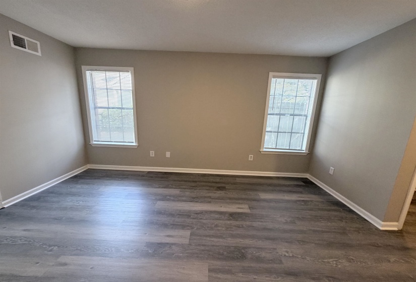 Spacious room featuring wood-finish flooring, neutral-toned walls, white trim, and two double-hung windows