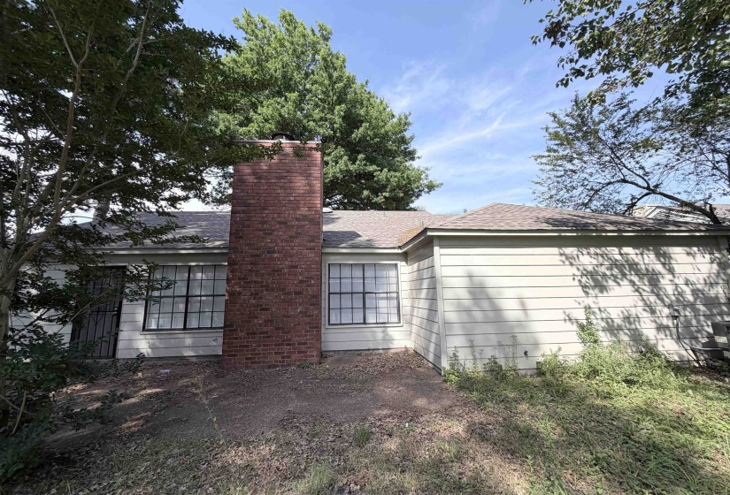 Exterior siding in a neutral tone with a prominent red brick chimney