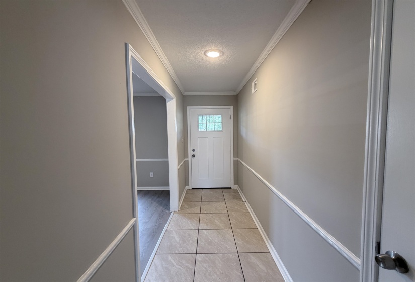 Entryway featuring light gray walls with chair rail and crown molding