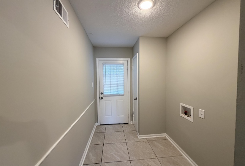 Utility space featuring tiled flooring, a rear exterior door with integrated blinds, and dedicated hookups for laundry appliances