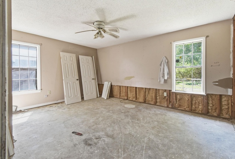 Room featuring two large windows, a ceiling fan with light fixture, and textured ceiling