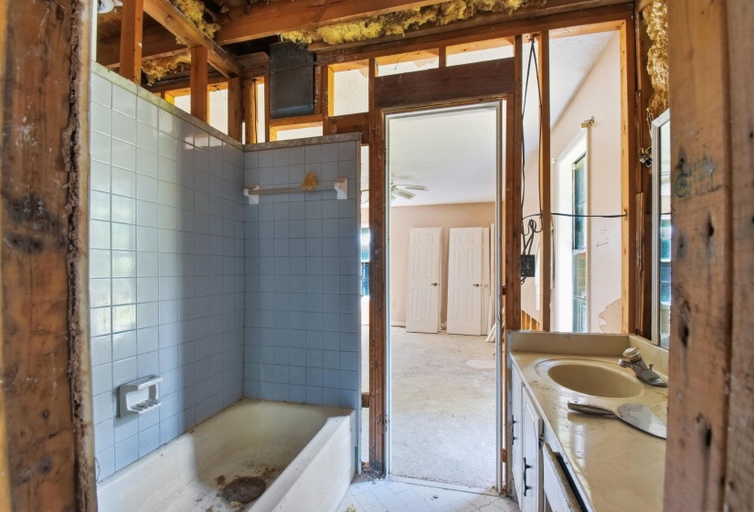Bathroom featuring a tiled bathtub and shower surround, along with a single vanity with an integrated sink