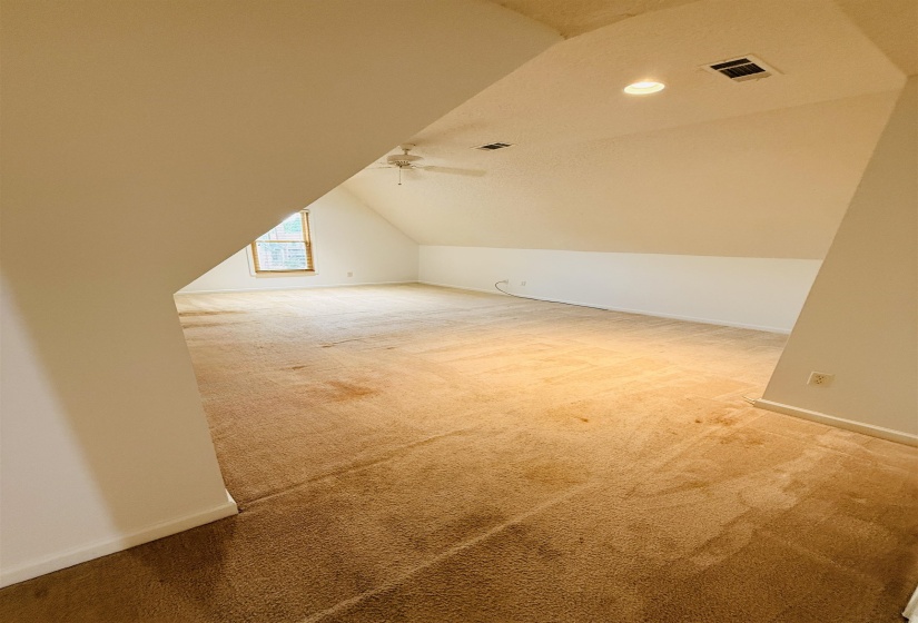 Spacious bonus room featuring sloped ceilings, recessed lighting, a ceiling fan, and a single window