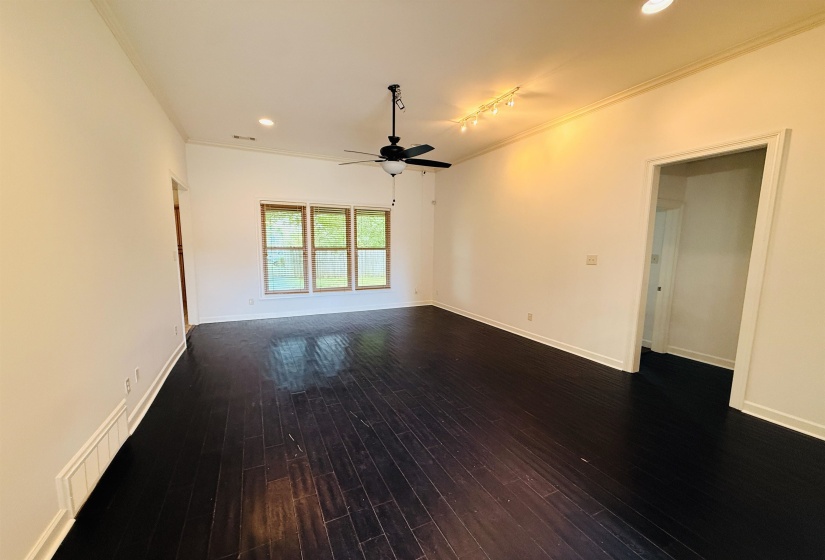 Spacious interior with dark wood-finish flooring, white walls, and crown molding