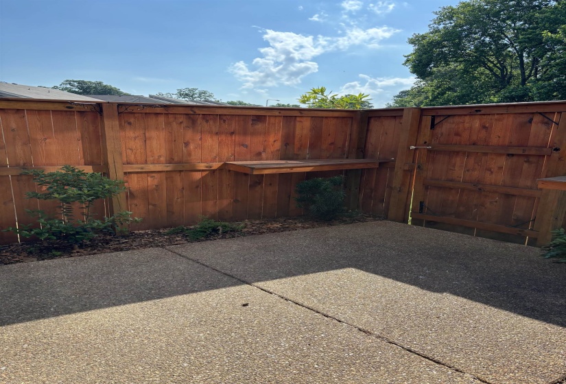 6 foot cedar fenced patio with shelves for displaying flowers or growing herbs. Small area for planting bushes or flowers.