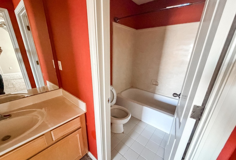 Bathroom featuring a vanity with a drop-in sink, wood-finish cabinetry, a mirror, and a bathtub with a shower
