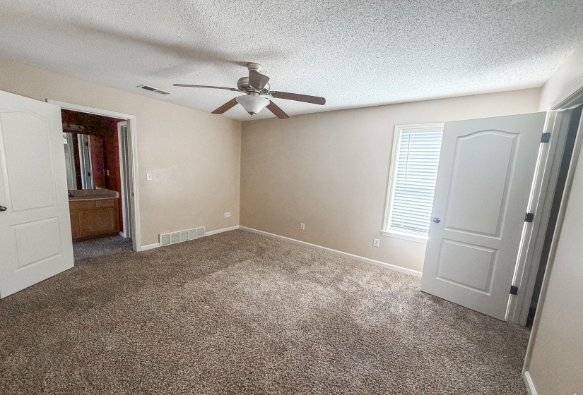 Carpeted room featuring a ceiling fan with light fixture, a window with blinds, and white interior doors