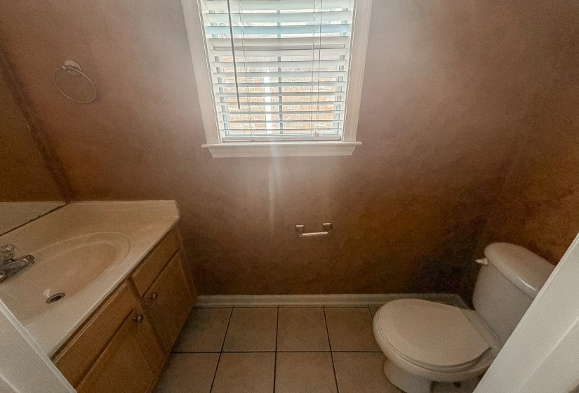 Bathroom featuring a light wood-finish vanity with an integrated sink, tiled flooring, and a window with blinds