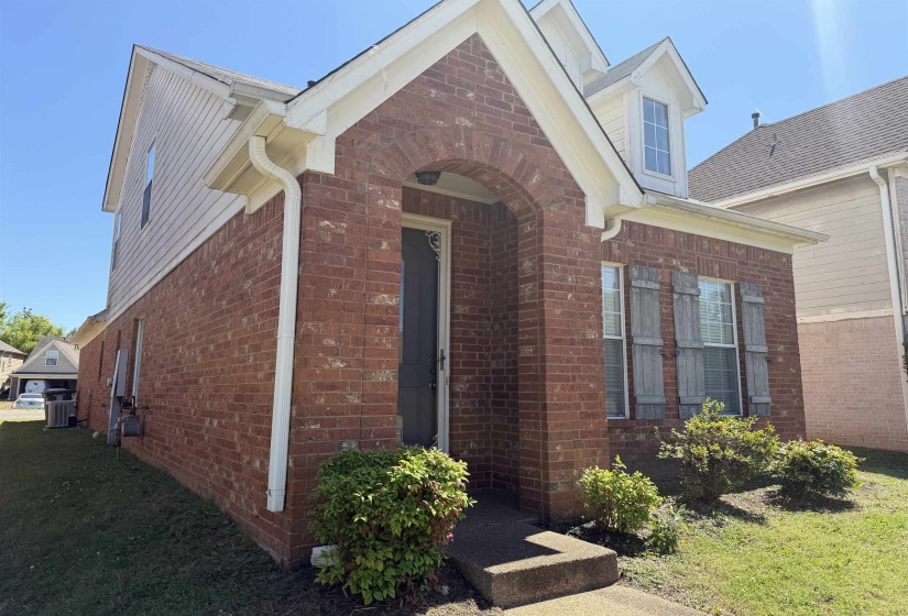 Brick facade with arched entryway, white siding, and a gabled dormer
