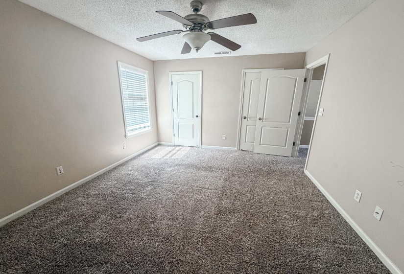Spacious interior room featuring plush, speckled carpeting and neutral wall tones