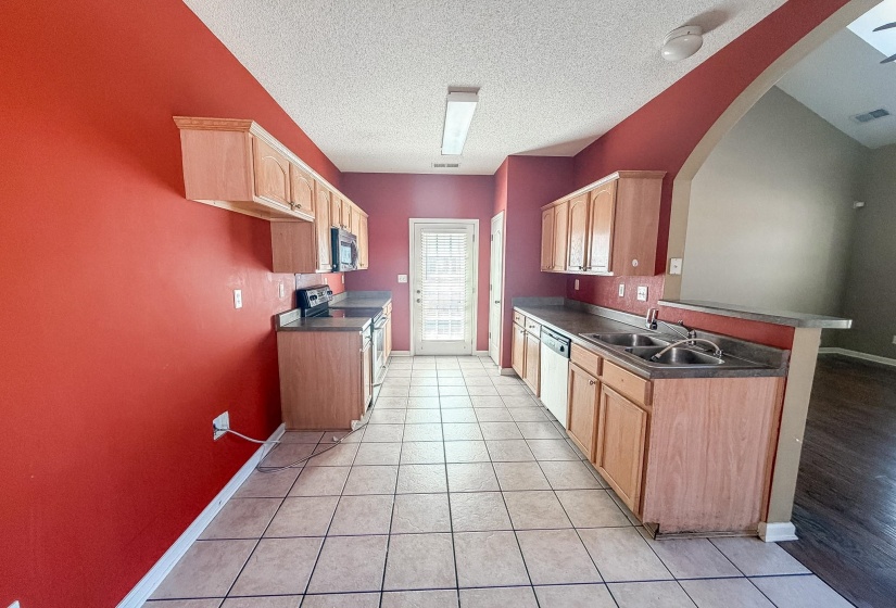 Kitchen featuring wood-finish cabinetry, dark countertops, and tile flooring