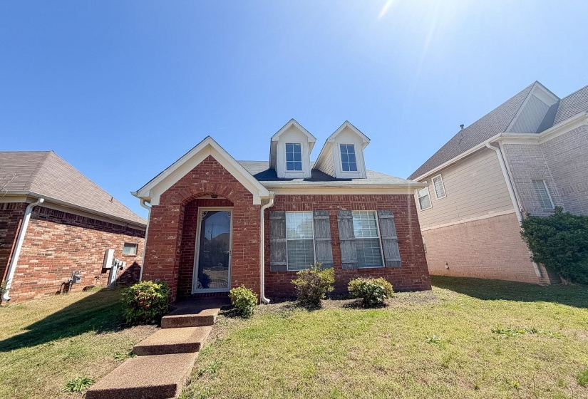 Brick exterior featuring dormer windows and decorative shutters