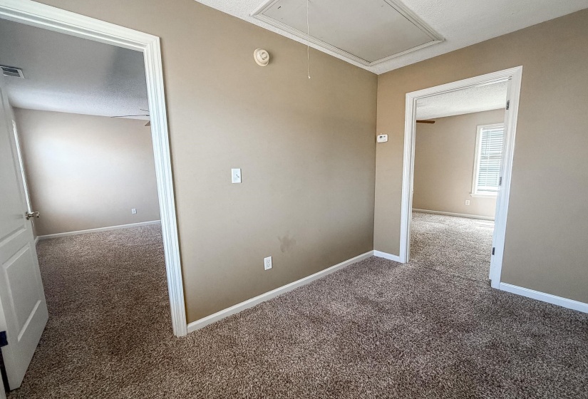 Carpeted hallway with neutral wall tones and white trim