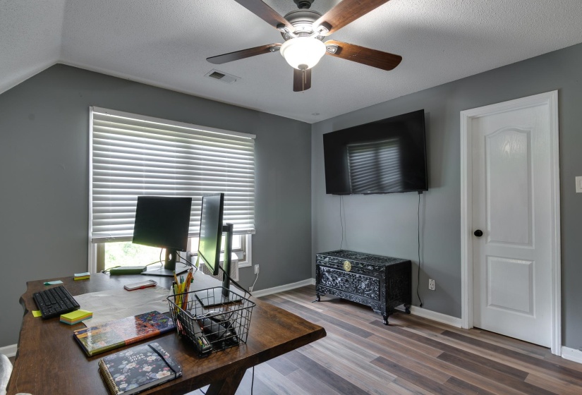 Room featuring wood-finish flooring, a ceiling fan with integrated lighting, and a window with horizontal blinds