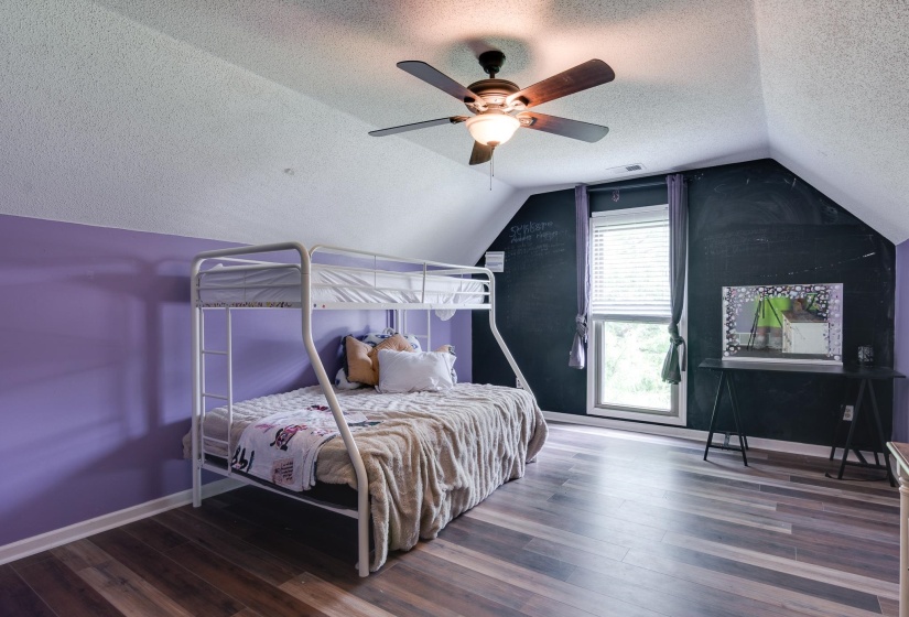 Room featuring wood-finish flooring, a sloped ceiling, and a ceiling fan with integrated lighting