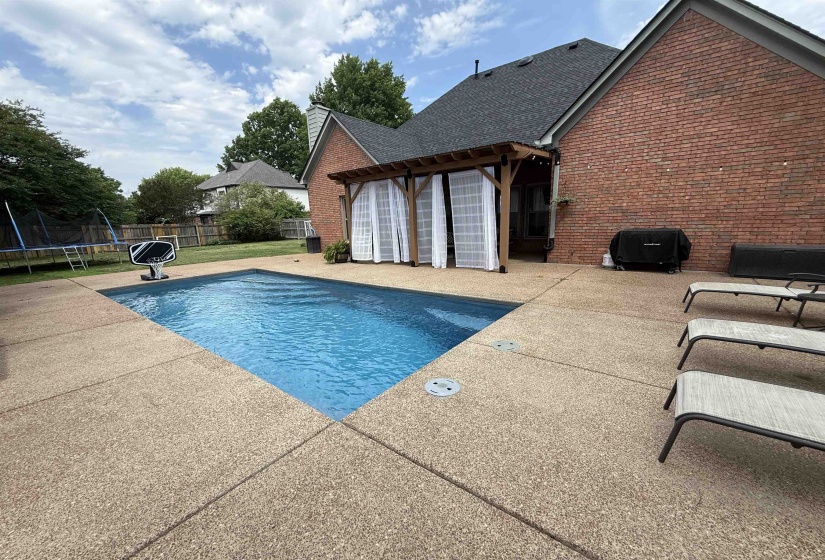 In-ground swimming pool with surrounding aggregate concrete patio
