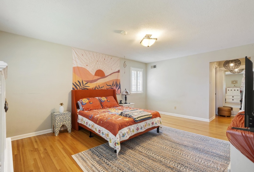 Spacious bedroom featuring light wood flooring and a recessed window with plantation shutters