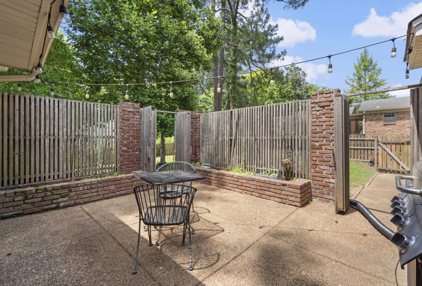 Concrete patio area featuring brick-based privacy fencing with vertical wood slats