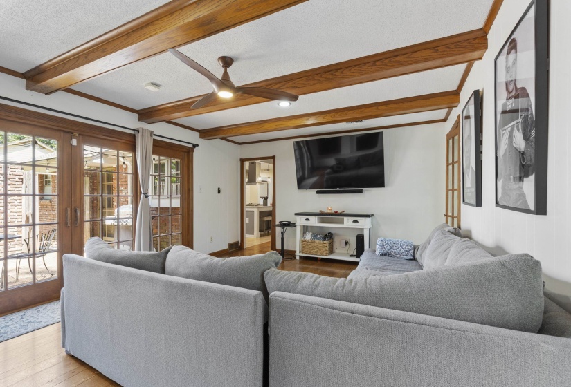Living area featuring exposed wood-finish ceiling beams and a ceiling fan