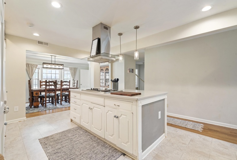 Kitchen island with an integrated cooktop and stainless steel ventilation hood