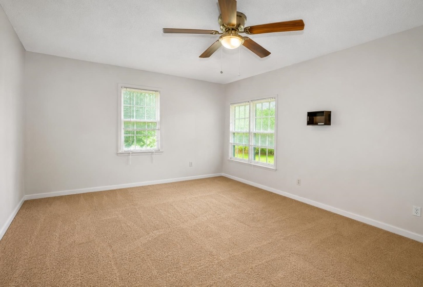 Neutral-toned carpet flooring and light wall paint define this spacious room
