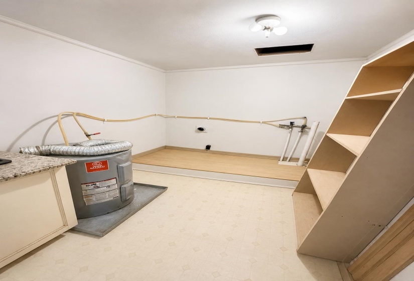 Utility room featuring a water heater, built-in shelving, and light-toned vinyl flooring