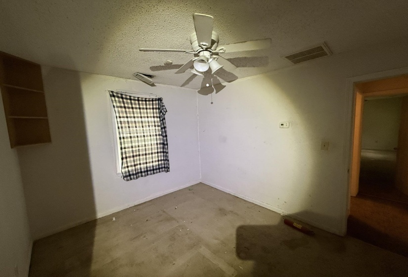Interior room featuring a ceiling fan, wall-mounted shelving, and a visible doorway to an additional interior space