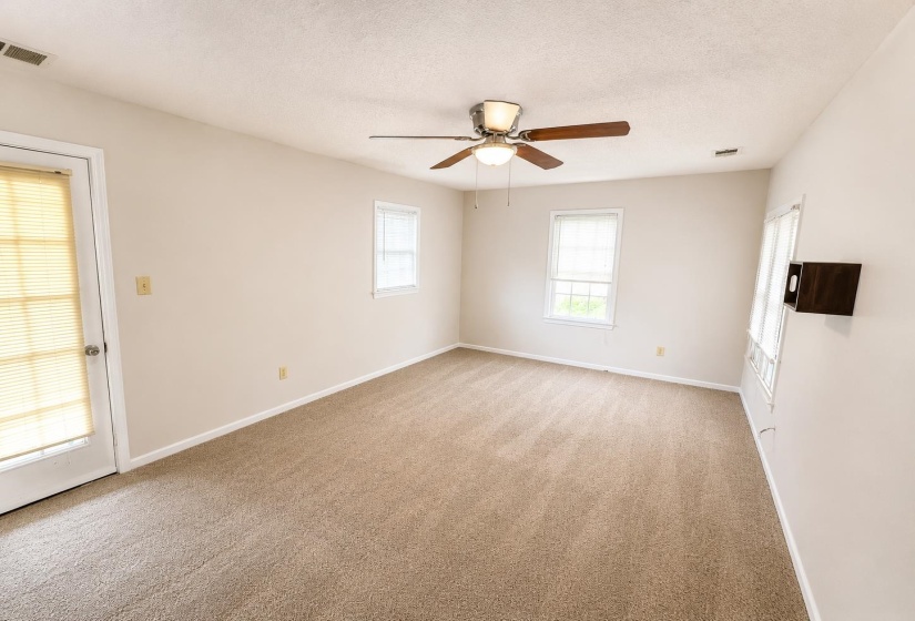 Carpeted room with a ceiling fan light fixture