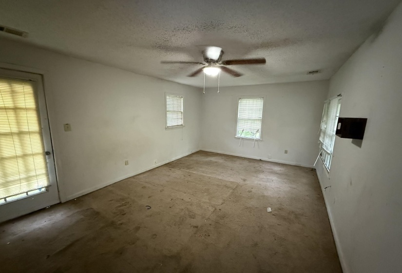 Spacious room with a ceiling fan, multiple windows, and a glass-paneled exterior door