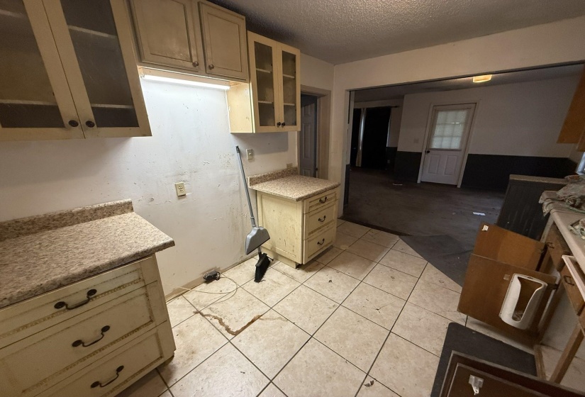 Kitchen area featuring light-colored cabinetry with glass inserts, complementary countertops, and tiled flooring