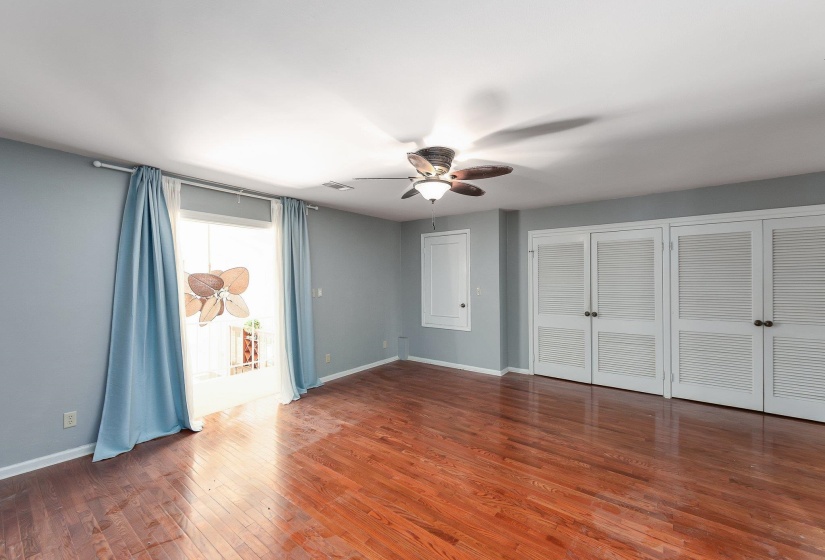 Unfurnished bedroom with visible vents, baseboards, wood finished floors, access to exterior, and multiple closets