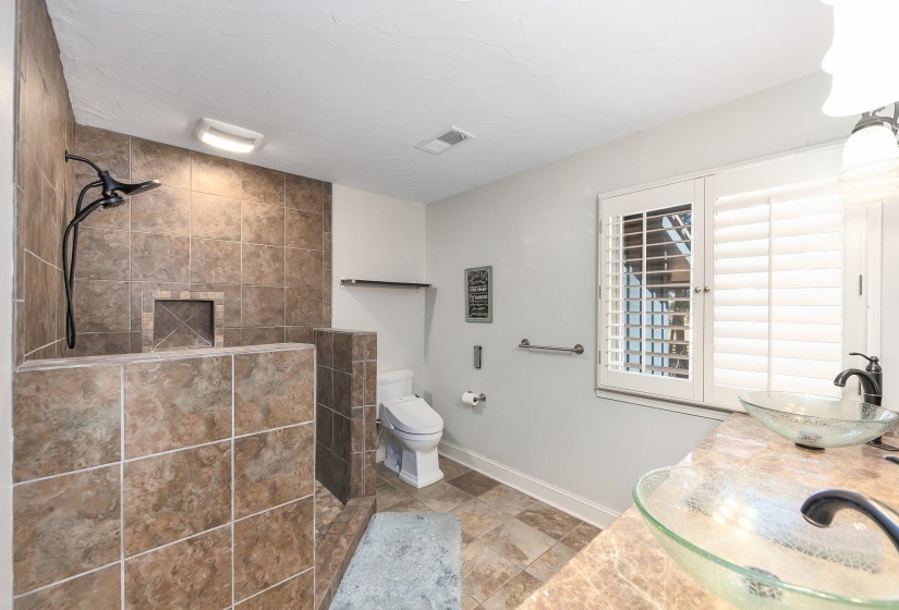 Full bathroom featuring toilet, baseboards, visible vents, and a tile shower