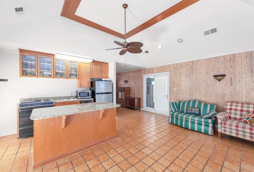 Kitchen with a breakfast bar, stainless steel appliances, lofted ceiling, visible vents, and glass insert cabinets